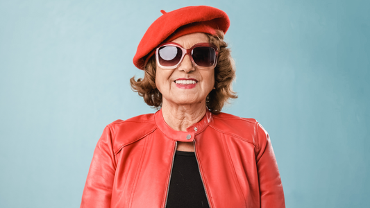 Older woman in red hat and red jacket wearing sunglasses to protect her eyes from the sun.